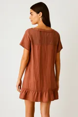 Vestido corto de algodón color verde, con escote redondo y mangas cortas. Presenta un calce ancho y holgado, con un detalle de volado o ruedo en el bajo.