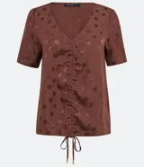 Blusa marrón de viscosa con escote en V, detalle fruncido en la parte delantera, manga corta y estampado de minihojas.