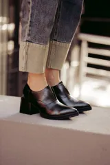 Zapato de cuero negro con diseño slip-on, texturas combinadas, punta fina y suela dentada.