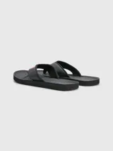 Ojotas negras Tommy Hilfiger con tira ancha de poliuretano acolchada y suela de goma EVA. Detalle de cinta distintiva con los colores de la marca en la tira.