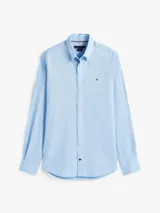 Camisa celeste de algodón Oxford con corte regular y mangas largas. Tiene cuello abotonado, cierre con botones y logo de Tommy Hilfiger bordado en el pecho.