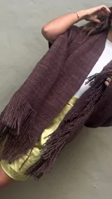 Ruana artesanal tejida en telar con lana merino de alta calidad, color marrón chocolate obtenido con teñido natural. Presenta un tejido grueso y textura visible, con flecos largos en el borde inferior.