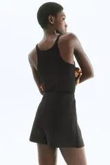 Short pollera tiro alto color negro, con elástico oculto en la cintura, pliegues y botones decorativos dorados en el frente.