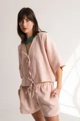 Blusa color crema confeccionada en lino, con mangas cortas, escote en V y lazos frontales.