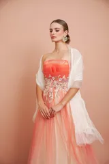 Vestido largo de fiesta, strapless, con busto drapeado y falda de tul con degradé de color coral a blanco. Presenta bordados florales en el corpiño.