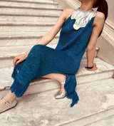 Vestido azul metálico con cuello plateado, sin mangas, corte recto, largo midi con flecos y tajos laterales.