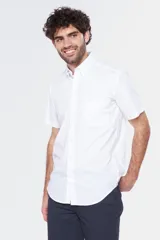 Camisa blanca de manga corta con cuello abotonado, bolsillo en el pecho y logo bordado.