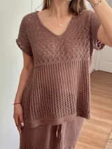 Remera color marrón de hilo de algodón con punto calado, escote en V, manga corta, silueta oversize y tajos laterales.