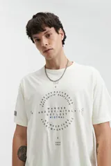 Remera color crema de manga corta con cuello redondo y estampado circular con texto en azul y negro.