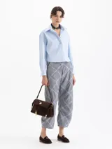 Camisa de algodón color celeste, de corte cropped y holgado, con cuello camisero y escote en V. Tiene mangas largas y puños con botones.