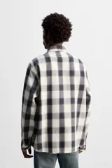 Camisa de hombre regular fit confeccionada en tejido de algodón a cuadros en tonos azul oscuro y verde oliva. Tiene cuello solapa, manga larga con puños abotonados, bolsillo de plastrón en el pecho y cierre frontal con botones.