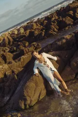 Vestido largo blanco con escote en V profundo y mangas largas acampanadas. Presenta aberturas en la parte delantera y detalles de cordones cruzados en el escote.