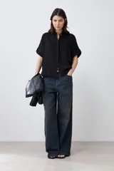 Camisa negra de manga corta con cuello clásico y cierre frontal con botones.