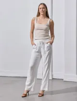 Pantalón de lino a rayas verticales color beige y blanco, con pretina ancha elastizada, lazo de ajuste y bolsillos inclinados.