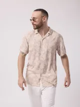 Camisa de hombre de manga corta con cuello cubano y estampado de hojas en tonos beige y blanco.