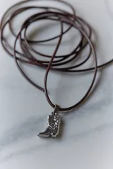 Dije dorado con forma de bota cowboy con detalles calados.