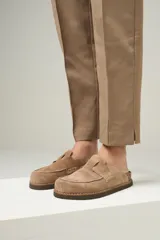 Zuecos color beige de cuero gamuzado, con costuras a la vista y suela de goma. Producto de industria uruguaya.