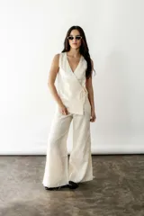 Blusa cruzada de lino color crudo, con escote en V, sin mangas y lazos laterales para ajustar.