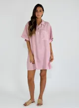 Vestido corto tipo camisola, color blanco, con cuello camisero, mangas cortas y bolsillo de parche con detalle de calado.