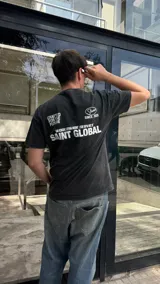 Remera negra con efecto gastado, corte oversized y estampado blanco en la espalda con las frases 'Crafted for the future', 'Worldwide service Saint Global' y 'Studios since 2025'.