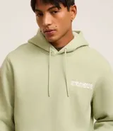 Buzo verde claro con capucha y cordón ajustable, de algodón con felpa. Tiene manga larga, barras ajustadas, bolsillo canguro y estampa frontal y trasera con la leyenda "Grand venture 1990".