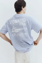 Remera celeste de algodón con cuello redondo y estampado frontal con la palabra "VIGNAUD" y un dibujo de una lancha.