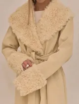 Abrigo trench maxi color beige con ribete de piel sintética en cuello y puños.