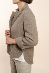 Chaqueta color crema de corte recto con cuello, solapa y bolsillos ojal. Forro solo en las mangas y terminaciones envivadas. Esquinas redondeadas y mangas con corte en puño que permiten transformarla en manga 3/4. Más larga en la espalda que en la delantera. Abrochadura con dos botones.