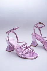 Sandalias negras con tiras lisas y trenzadas en el empeine, y una tira trenzada que se ajusta al tobillo con hebilla. Tienen un tacón geométrico.