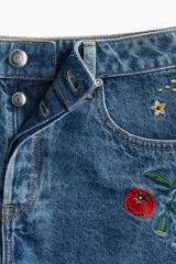 Short de jean de tiro alto con bordados de flores rojas, amarillas y blancas.
