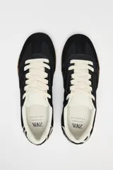 Zapatillas deportivas negras con detalle de estampado animal en la parte trasera, suela color caramelo y ajuste con cordones.