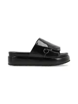 Sandalia de cuero color negro con tira ancha sobre el empeine, ajuste con velcro y aplique metálico circular.