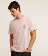 Remera de algodón color rosa claro, de corte clásico, con cuello redondo y manga corta. Presenta un pequeño estampado de un timón en el pecho y un estampado con letras en la espalda.