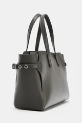 Bolso mini shopper de cuero sintético color gris oscuro, con doble asa de mano y detalles de ojales metálicos en los laterales. Incluye asa extraíble para llevar como bandolera y cierre magnético.