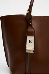 Bolso negro tipo shopper con asa de hombro, detalle de colgador y bolsillo interior maxi. Cierre mediante imán.
