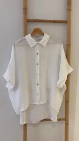 Camisa marrón de lino con botones blancos, corte holgado y mangas cortas.