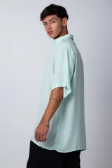 Camisa celeste de manga corta con cuello clásico y calce oversize.