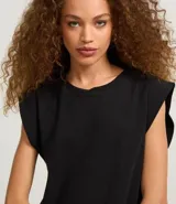 Blusa sin mangas, color blanco, confeccionada en tejido rib de algodón, con cuello redondo y hombreras marcadas.