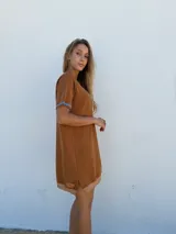Vestido corto marrón tejido en hilo, con mangas cortas y cuello redondo.