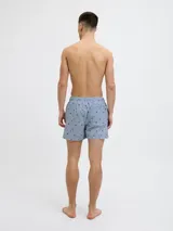 Short de baño celeste con rayas verticales blancas y estampado de motivos marinos en azul. Cuenta con cintura elástica ajustable con cordón y bolsillos laterales.