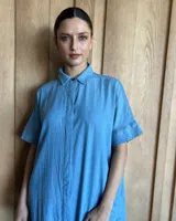 Vestido túnica celeste de lino con rayas verticales blancas, corte recto, cuello camisero y mangas cortas.