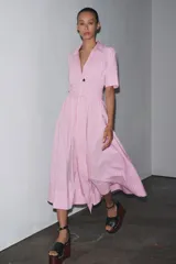 Vestido camisero midi de popelina a rayas verticales rosas y blancas, con cuello solapa, manga corta, bolsillos de parche en el pecho, cinturón de lazo ajustable y cierre frontal con botones.