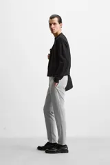 Pantalón negro de corte slim fit, confeccionado en tejido elástico. Cuenta con cintura elástica, bolsillos frontales y traseros de vivo. Cierre frontal con cremallera y botón.
