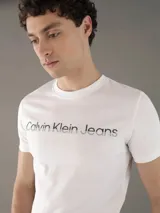 Remera blanca de algodón con cuello redondo y mangas cortas. Estampado frontal con el logo "Calvin Klein Jeans" en color negro.
