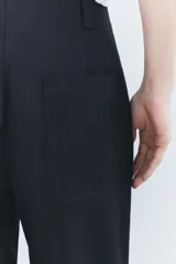 Pantalón color beige de corte ancho, con tiro medio, trabillas en la cintura y raya planchada.
