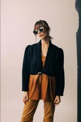 Blazer negro con solapas y cierre con botón de madera. Presenta corte a la cintura y parte inferior color marrón.