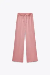 Pantalón de tiro alto color rosado, con cintura elástica ajustable con cordones, bolsillos delanteros y pernera ancha. Tejido con efecto arrugado.