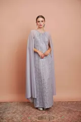 Vestido largo de encaje color plata con brillos y cuello halter. Incluye capa de gasa larga.