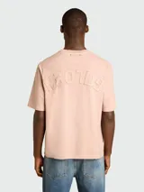 Remera de algodón color rosa pálido, con cuello redondo y manga corta. Presenta un dobladillo deshilachado en el cuello y en los bordes de las mangas.