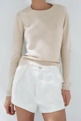 Jersey color crema de punto liso con cuello redondo y manga larga, confeccionado con lana.